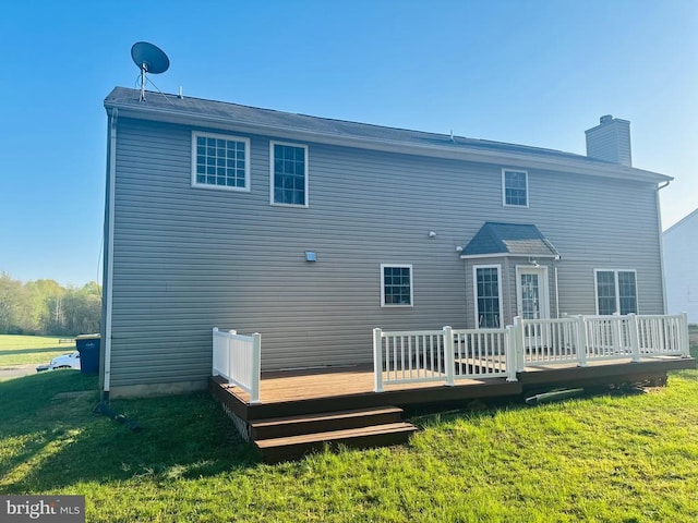 back of house with a wooden deck, a lawn, and a chimney