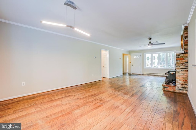  - unfurnished living room featuring a wood stove, ceiling fan, a baseboard heating unit, hardwood / wood-style floors, and crown molding