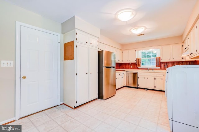  - kitchen featuring stainless steel appliances, washer / dryer, white cabinetry, light countertops, and decorative backsplash