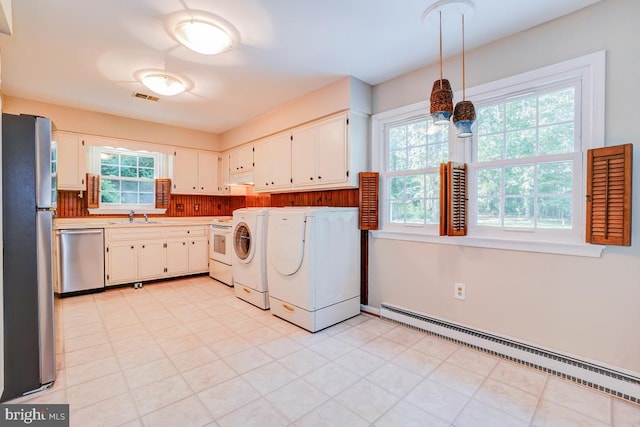  - laundry room featuring separate washer and dryer, a baseboard heating unit, cabinet space, and light floors