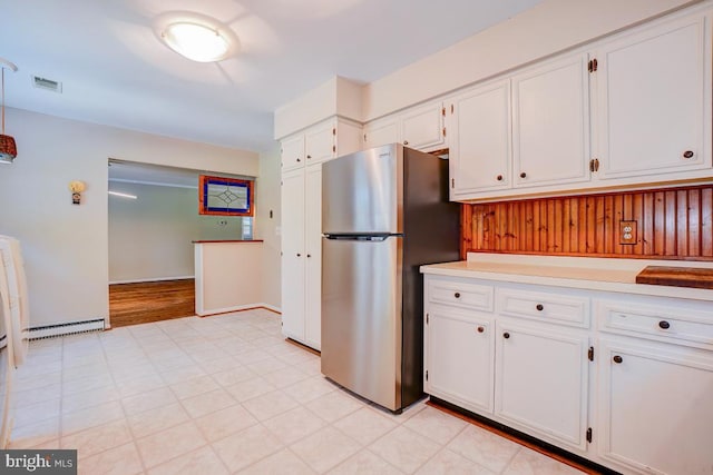  - kitchen with freestanding refrigerator, white cabinets, a baseboard heating unit, light countertops, and light flooring