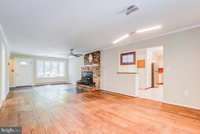  - unfurnished living room featuring a baseboard radiator, a wood stove, crown molding, light wood-type flooring, and ceiling fan