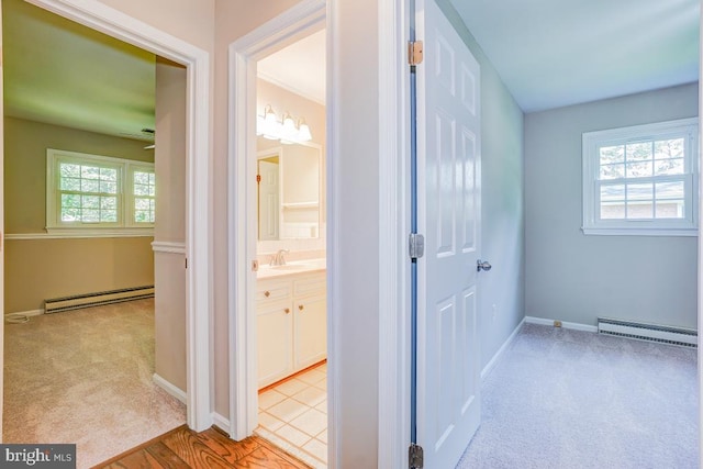  - hallway featuring a baseboard radiator, light colored carpet, and plenty of natural light