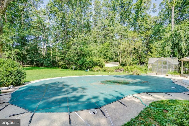  - view of swimming pool with a lawn, an exterior structure, a covered pool, and an outdoor structure