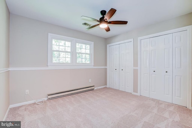  - unfurnished bedroom with a baseboard radiator, multiple closets, carpet, and a ceiling fan