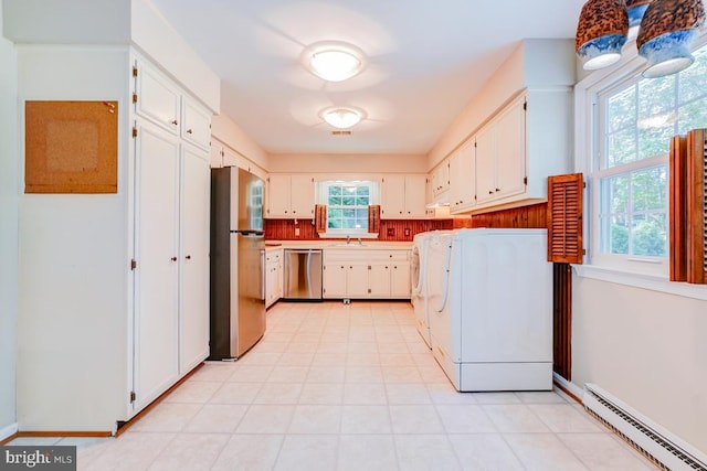  - laundry area with baseboard heating, washer / clothes dryer, and plenty of natural light