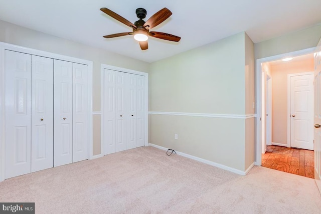  - unfurnished bedroom featuring multiple closets, carpet flooring, and ceiling fan
