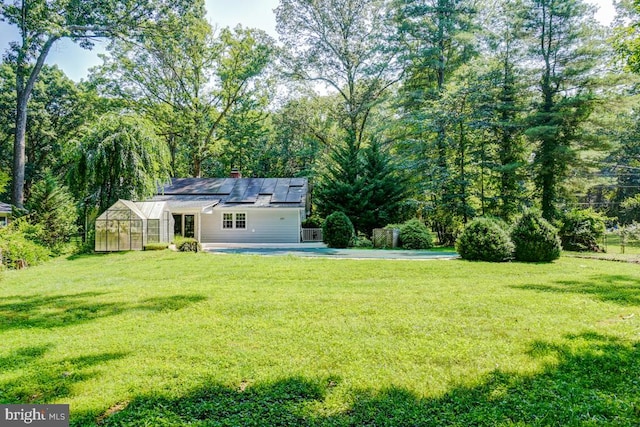  - view of grassy yard with a greenhouse and an outdoor structure