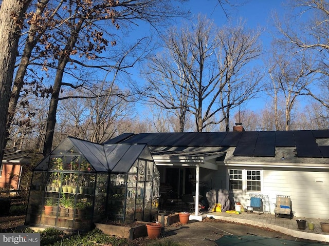  - back of house with solar panels and a chimney