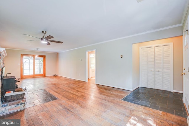  - unfurnished living room with ceiling fan, crown molding, a wood stove, and wood finished floors