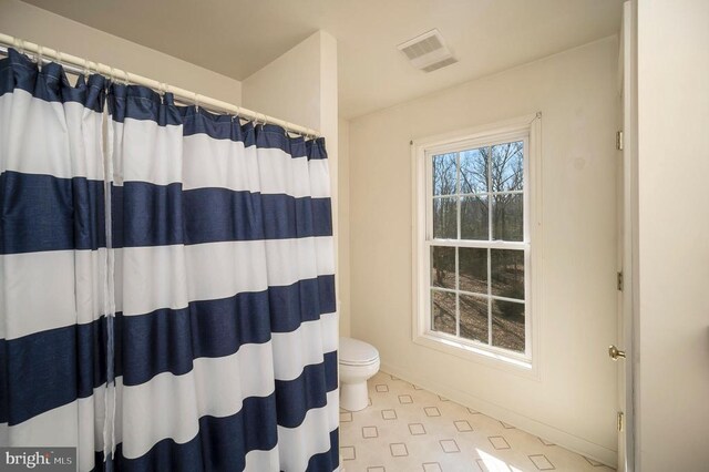 8128 Shirley Rd, Spotsylvania, VA 22551 - bathroom with toilet, baseboards, and a shower with shower curtain