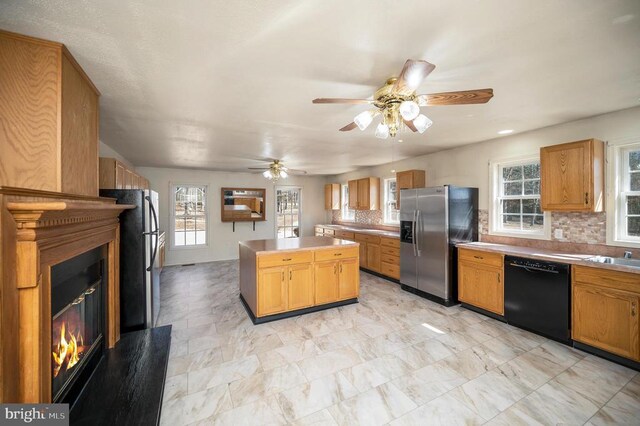8128 Shirley Rd, Spotsylvania, VA 22551 - kitchen with black dishwasher, stainless steel fridge, a glass covered fireplace, a center island, and tasteful backsplash