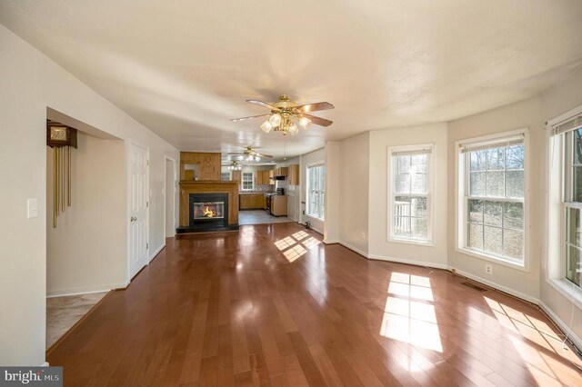 8128 Shirley Rd, Spotsylvania, VA 22551 - unfurnished living room featuring wood finished floors, plenty of natural light, a glass covered fireplace, and a ceiling fan