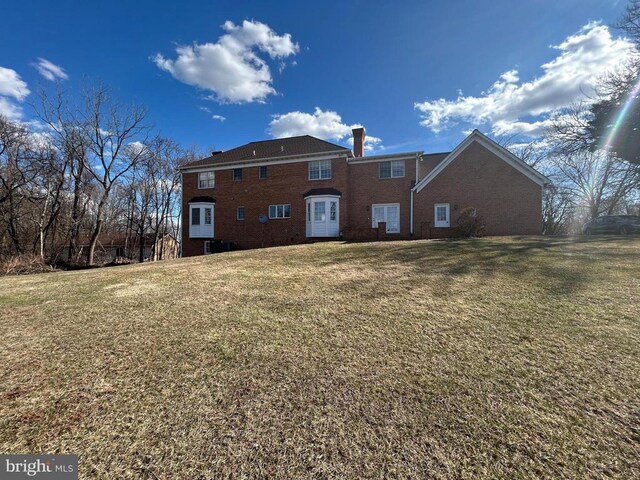  - rear view of property with a chimney, a yard, and brick siding