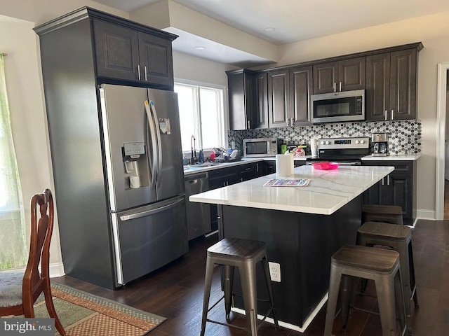  - kitchen with appliances with stainless steel finishes, dark wood-type flooring, light countertops, and a breakfast bar area