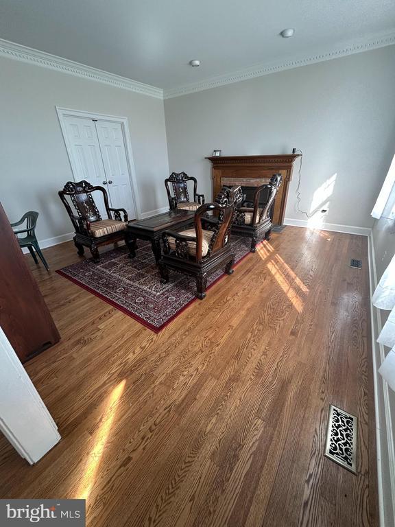  - living room featuring wood finished floors, ornamental molding, and a fireplace