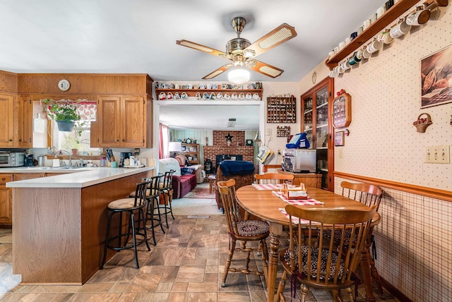 14335 S E Side Hwy, Grottoes, VA 24441 - dining space featuring a ceiling fan, wallpapered walls, stone finish floor, wainscoting, and a brick fireplace