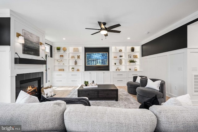 11302 Radcliff Ter, Spotsylvania, VA 22551 - living area featuring a ceiling fan, wood finished floors, a decorative wall, a glass covered fireplace, and a wainscoted wall