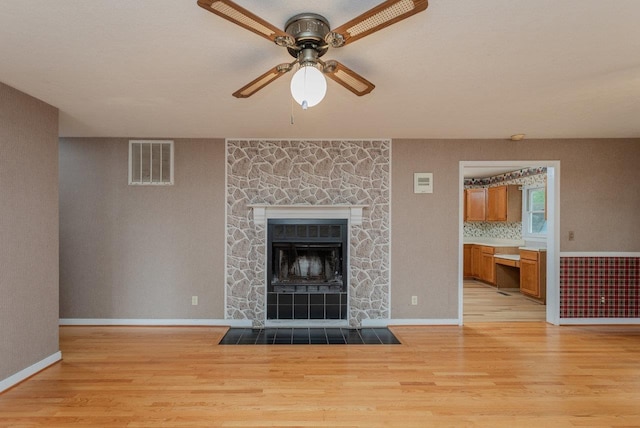 22 Loblolly Rd, Palmyra, VA 22963 - unfurnished living room with light wood-type flooring, a ceiling fan, and a stone fireplace