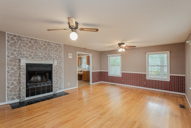 22 Loblolly Rd, Palmyra, VA 22963 - unfurnished living room with wood finished floors, a ceiling fan, a wainscoted wall, and a stone fireplace