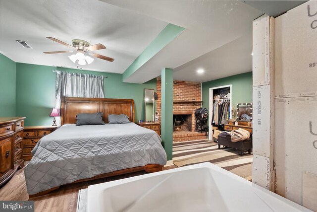 - bedroom featuring a brick fireplace, wood finished floors, a ceiling fan, and a closet