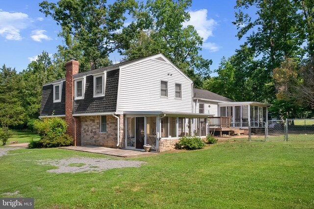  - back of property featuring a sunroom, a chimney, stone siding, a gate, and a shingled roof