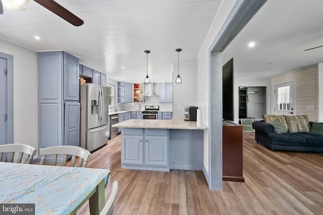 - kitchen with appliances with stainless steel finishes, a peninsula, light wood-type flooring, wall chimney range hood, and a ceiling fan