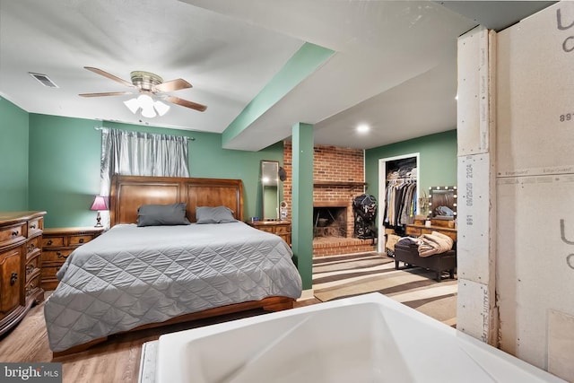  - bedroom with a fireplace, wood finished floors, a closet, and ceiling fan