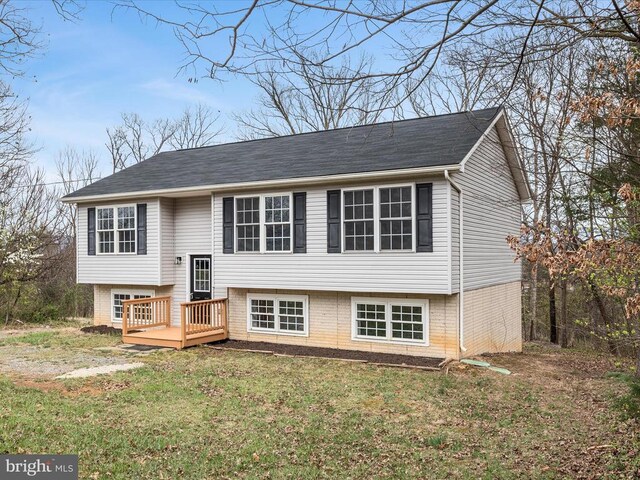 raised ranch featuring a front lawn, brick siding, and a deck
