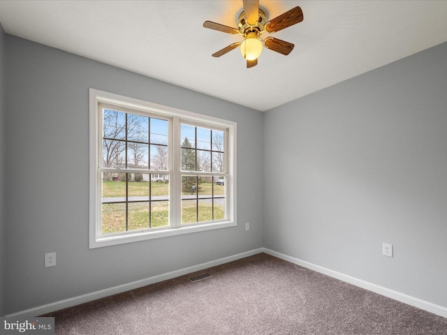 unfurnished room with carpet, baseboards, a ceiling fan, and visible vents
