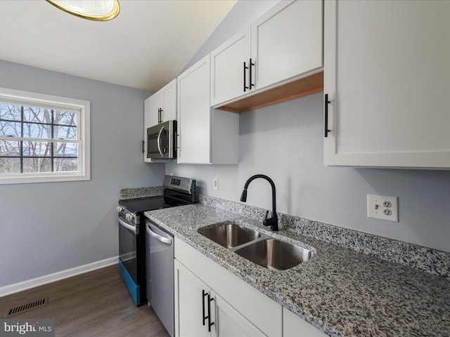 kitchen featuring a sink, stainless steel appliances, light stone counters, visible vents, and white cabinets