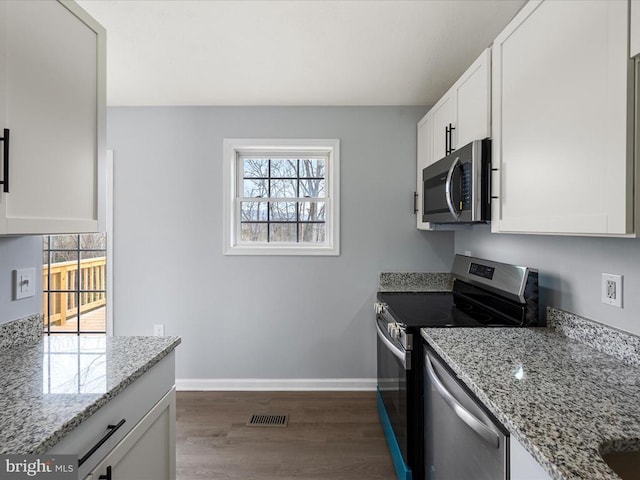 kitchen featuring appliances with stainless steel finishes, healthy amount of natural light, dark wood-style floors, and light stone counters