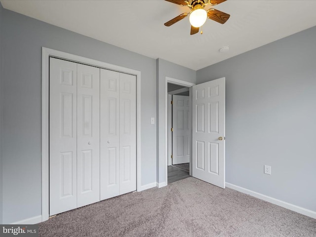 unfurnished bedroom with carpet flooring, baseboards, a closet, and a ceiling fan