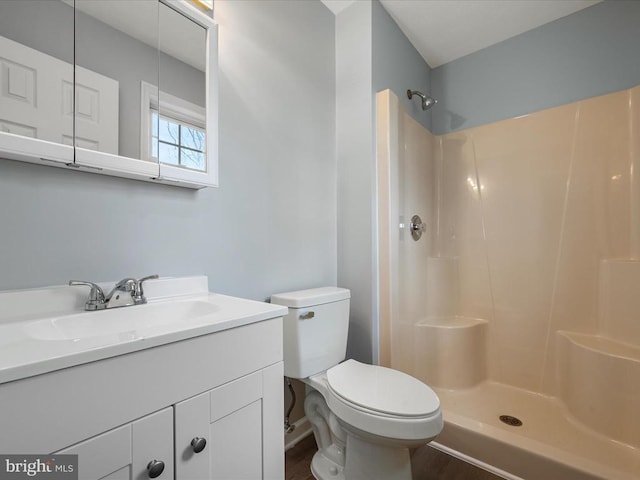 bathroom featuring walk in shower, vanity, toilet, and wood finished floors