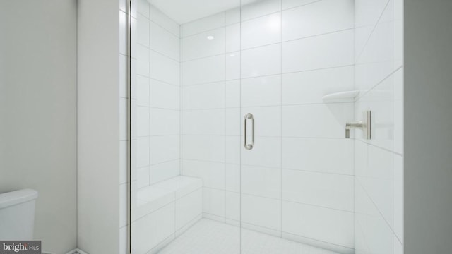 bathroom featuring toilet and a shower stall