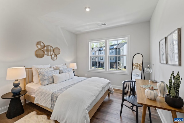 bedroom with baseboards, visible vents, and wood finished floors