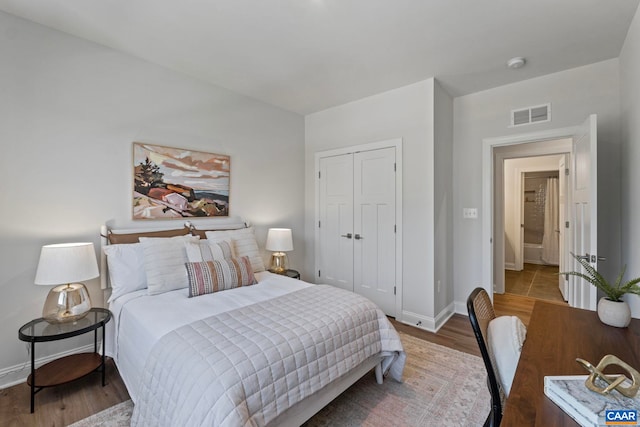 bedroom with baseboards, a closet, visible vents, and wood finished floors