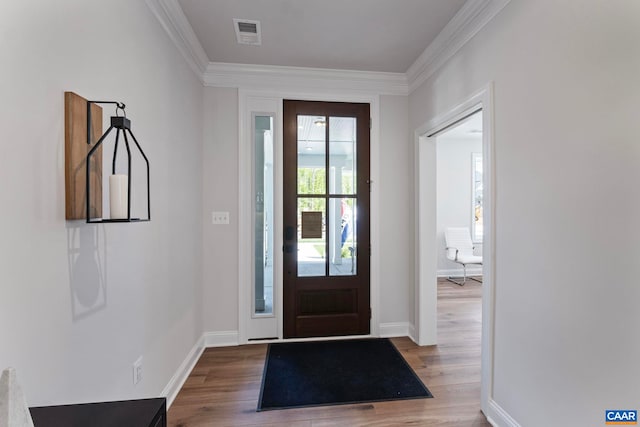entryway with crown molding, visible vents, wood finished floors, and baseboards