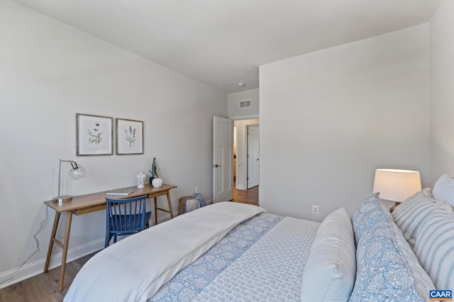 bedroom with visible vents, wood finished floors, and baseboards