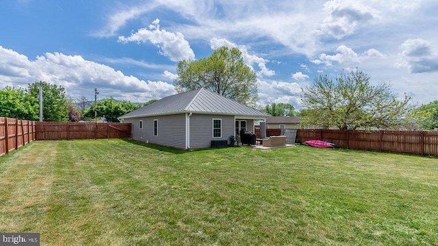 back of house with a yard, metal roof, and a fenced backyard