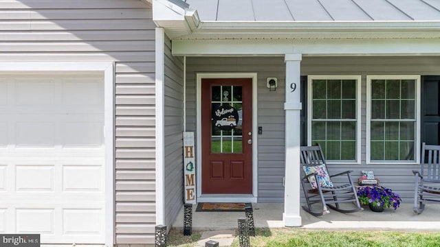 property entrance featuring a porch, an attached garage, metal roof, and a standing seam roof