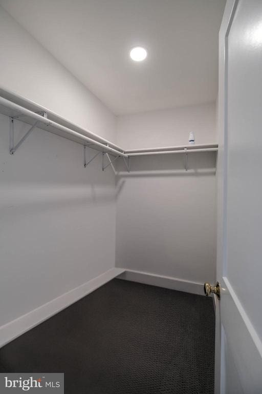 spacious closet featuring dark carpet
