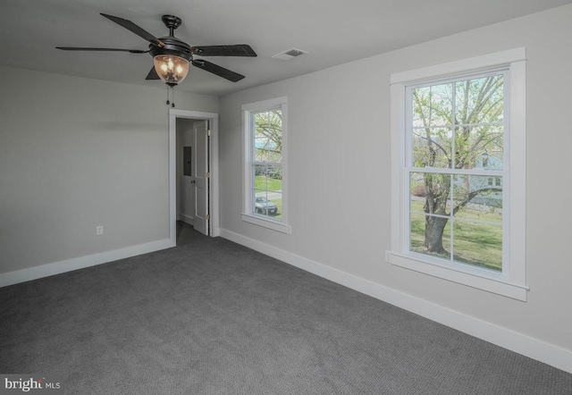 spare room featuring dark colored carpet, baseboards, and ceiling fan