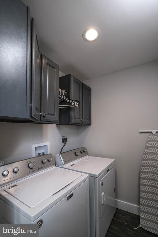 laundry room with washer and clothes dryer, cabinet space, baseboards, and dark wood-style flooring