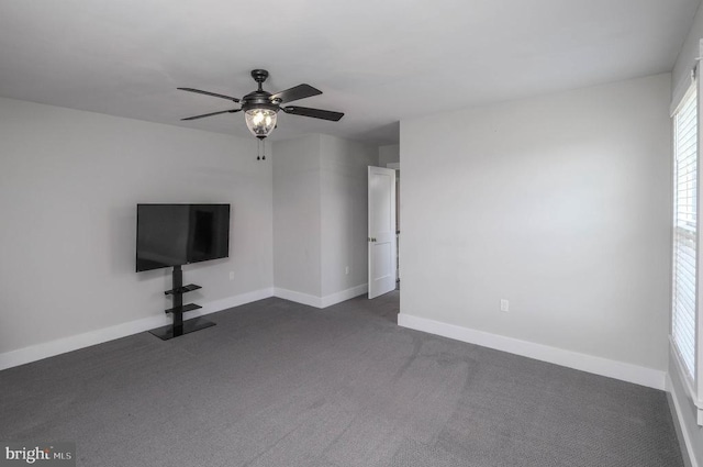 unfurnished living room with baseboards, a ceiling fan, and dark colored carpet