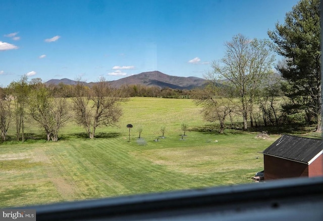 view of green lawn featuring a mountain view
