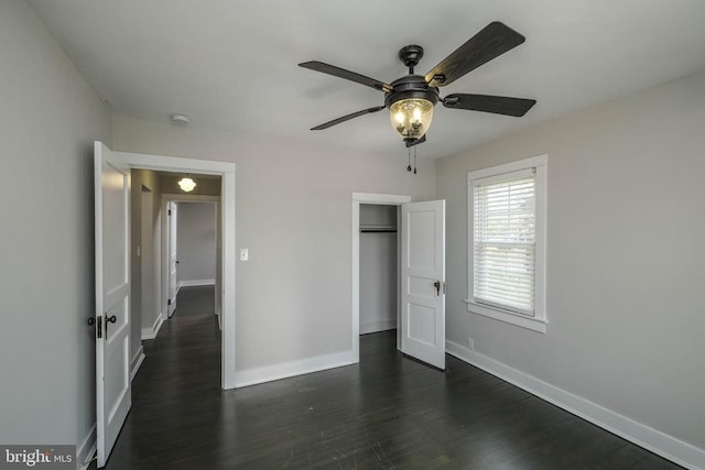 unfurnished bedroom with dark wood finished floors, baseboards, a closet, and a ceiling fan