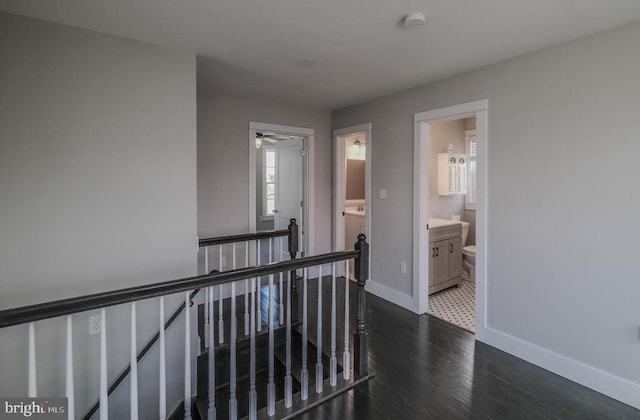 hallway featuring an upstairs landing, baseboards, and dark wood finished floors
