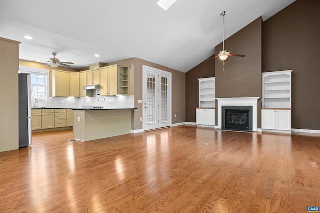 kitchen with freestanding refrigerator, under cabinet range hood, open shelves, and ceiling fan