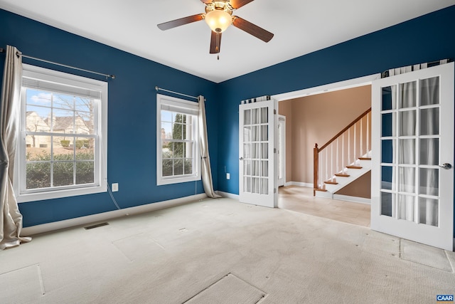 empty room with stairs, french doors, visible vents, carpet floors, and a ceiling fan